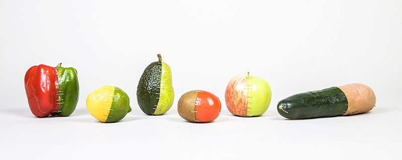 A collection of fruits and vegetables that have been cut in half and stapled back together differently, appearing like 2-part wholes of different items.